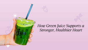 A hand holds up a plastic cup of dark green juice with a blue straw. The light purple background contains text that reads: "How Green Juice Supports a Stronger, Healthier Heart."