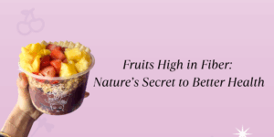 A person holds an açaí bowl topped with fruits, including diced pineapple and strawberries. The background is pink with the text: "Fruits High in Fiber: Nature's Secret to Better Health."